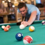 Young man playing pool in a bar (focus on pool tab